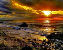 Каменистый пляж и солнце над морем