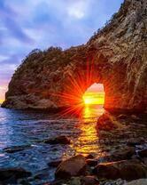 Солнце у скалы в море