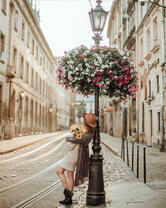 Девушка на улице старого города под цветочным фонарем