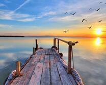 Восходящее солнце над тихим озером с причалом