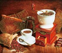 Чашечка с кофе и зерна в кофемолке