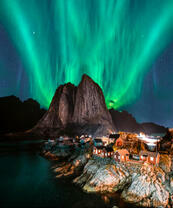 Северное сияние над городом у скалы