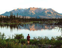Мужчина на берегу озера у горы