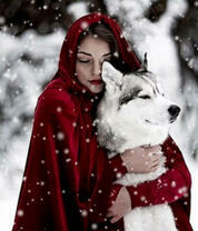 Девушка в красном обнимает хаски под снегом