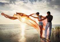 Влюблённая пара над морем на фоне солнца