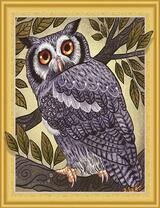 Серая сова в ветвях дерева