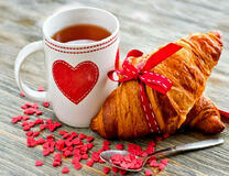 Свежий круассан с ленточкой и горячий чай