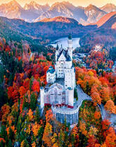 Белый замок среди осеннего леса в горах