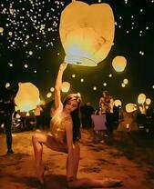 Девушка запускает в небо китайский фонарик