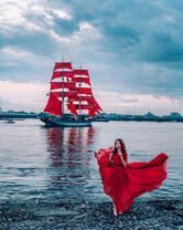 Девушка в красном платье на фоне парусника