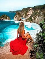 Девушка в красном на скале над морем