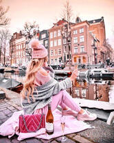 Девушка с вином на берегу городской реки