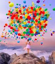 Девушка с шариками на скале у моря