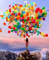 Девушка с разноцветными шарами на вершине скалы